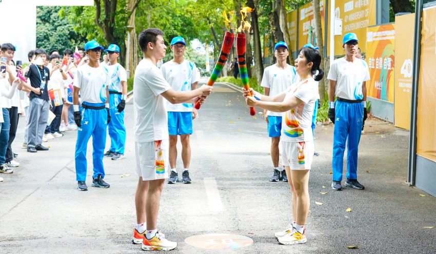 火炬手正在傳遞交接。成都大運會執委會供圖