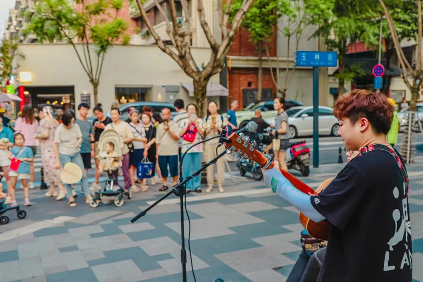 街頭藝人的表演深深吸引路人。玉林街道辦事處供圖