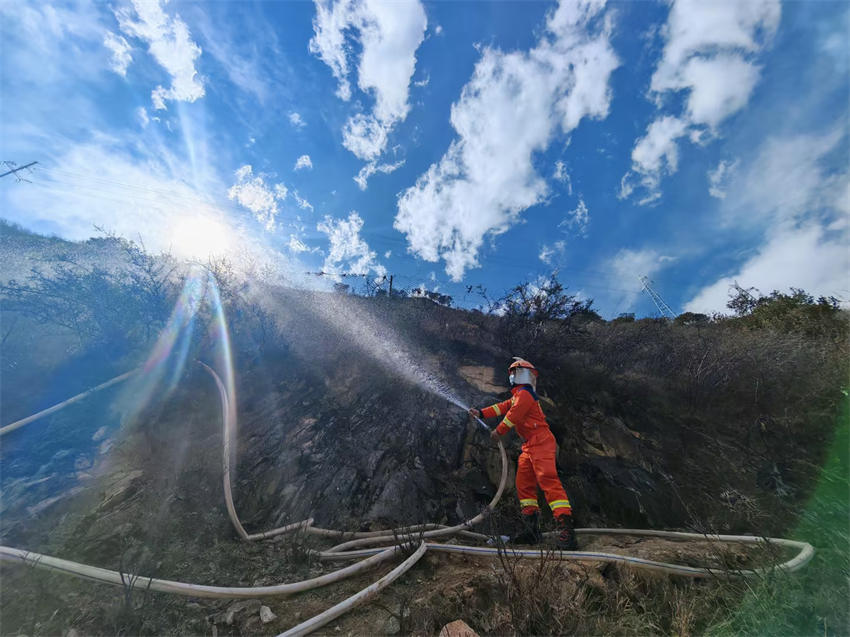 眉山市消防救援支隊救援人員利用40水帶出槍，對雅江縣降央寺周邊植被進行澆灌、降溫冷卻。四川省消防救援總隊供圖